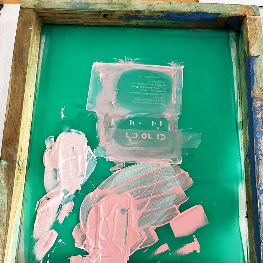 Detail of ainoah brand logo being screen printed with pink coloured pigments.