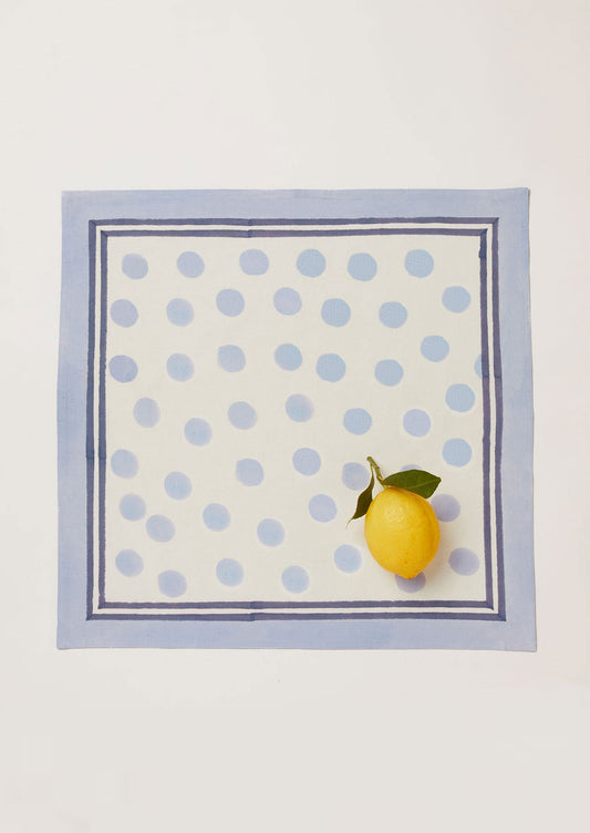 Single pale blue napkin in a polka dot block printed design with a lemon placed in the bottom corner.