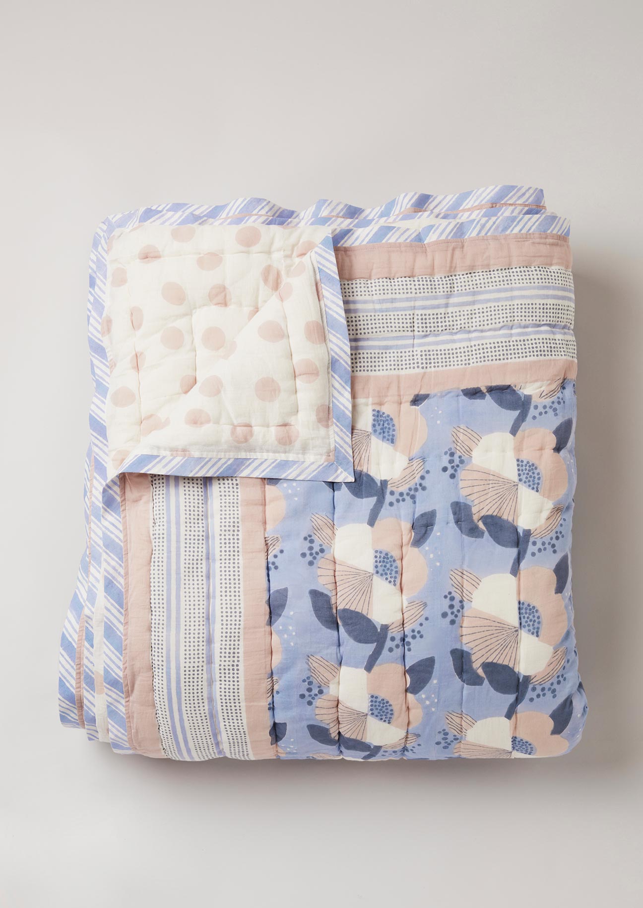 Quilted cotton bedspread with block printed floral design and pink polka dot on the reverse side