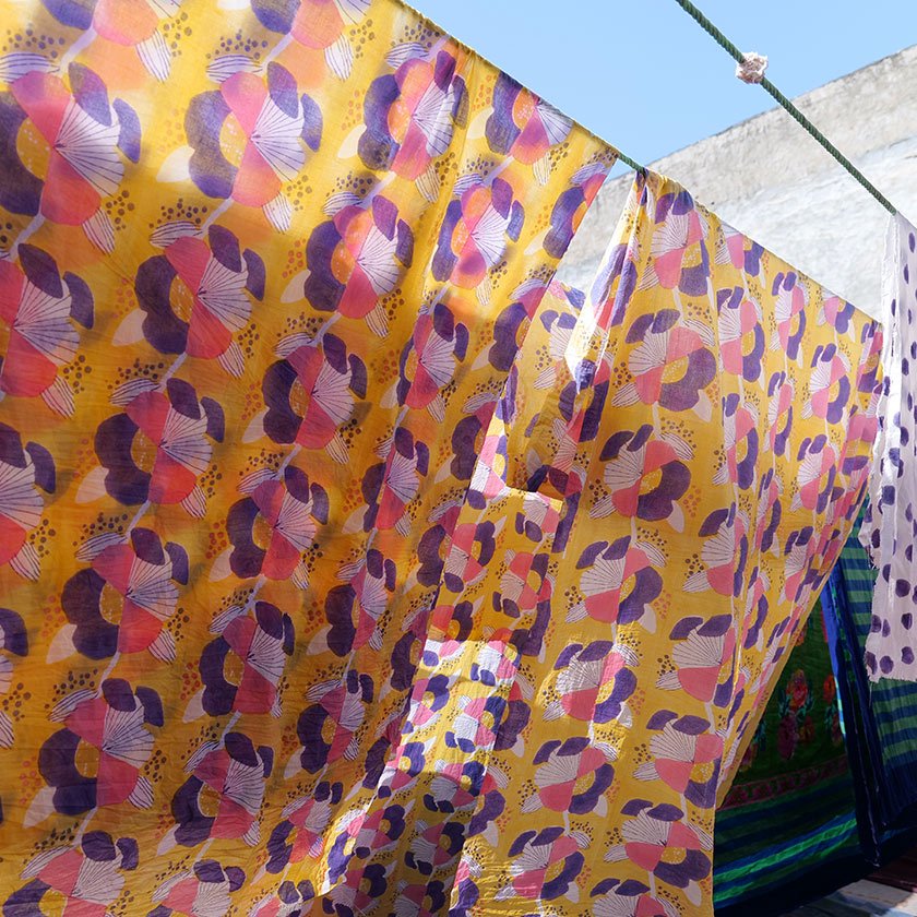Yellow floral block printed fabric hanging on a washing line and drying out in the sun.