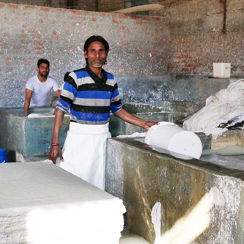 Two men mixing cotton fibers and water to make recycled paper.