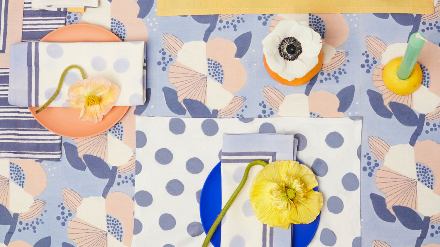 Tablescape with a collection of block printed napkins, tablemats and matching tablecloth, with real flower decorations.