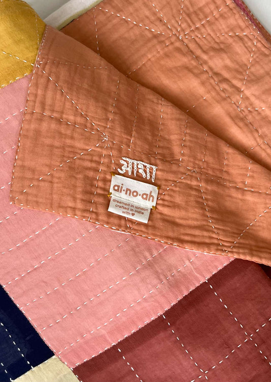 Detail of kantha stitching and artisan's signature on a patchwork quilt