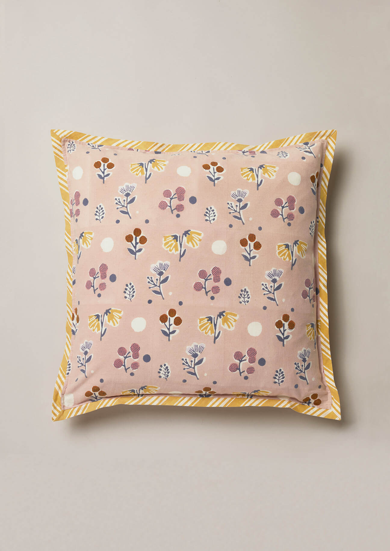 Dusty pink hand block print cushion with blue, yellow and blue flowers and contrast yellow stripe edging.