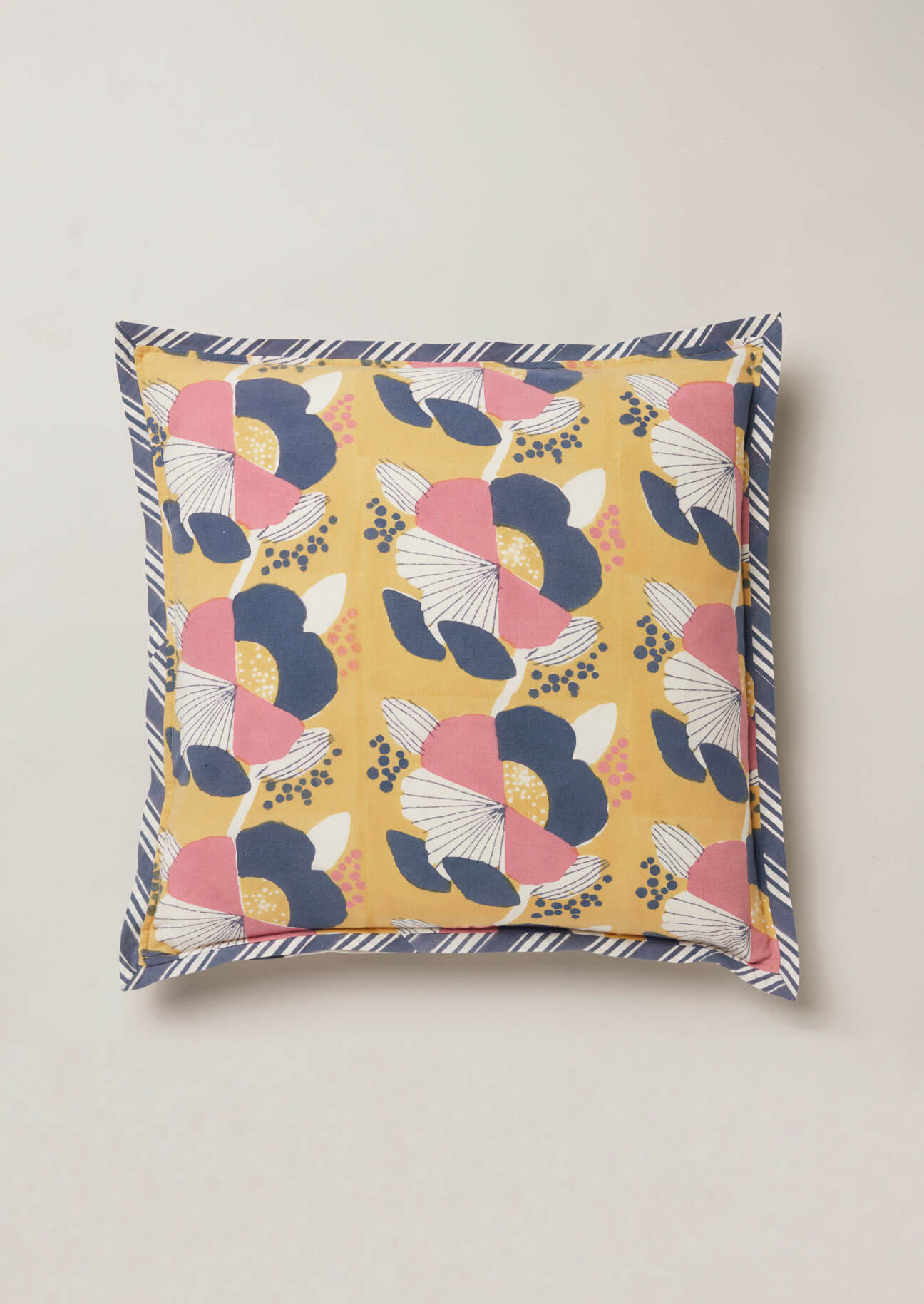 Ochre block print cush ion with navy and pink large scale flower designand contrast navy stripe edging.