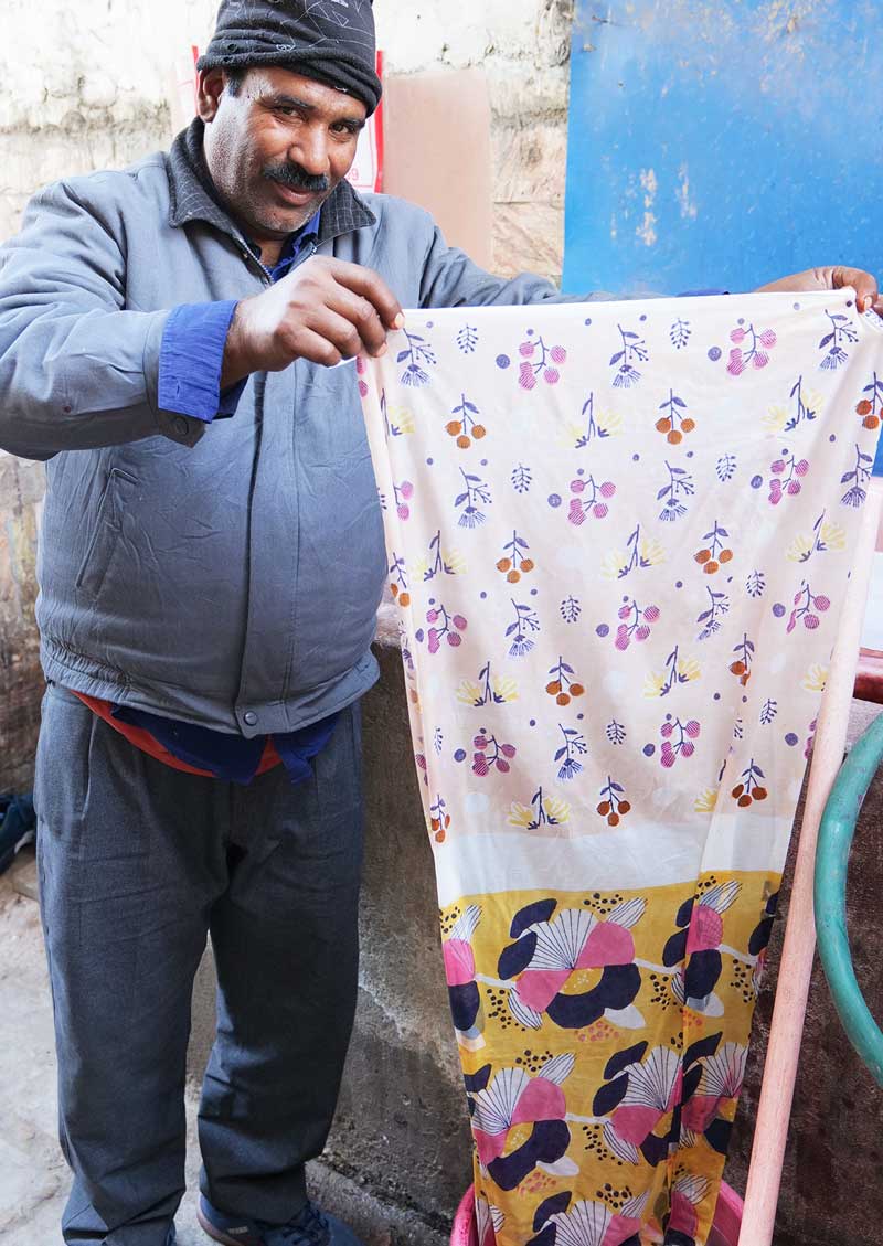 Block printing artisan washing freshly printed fabrics in Jaipur.