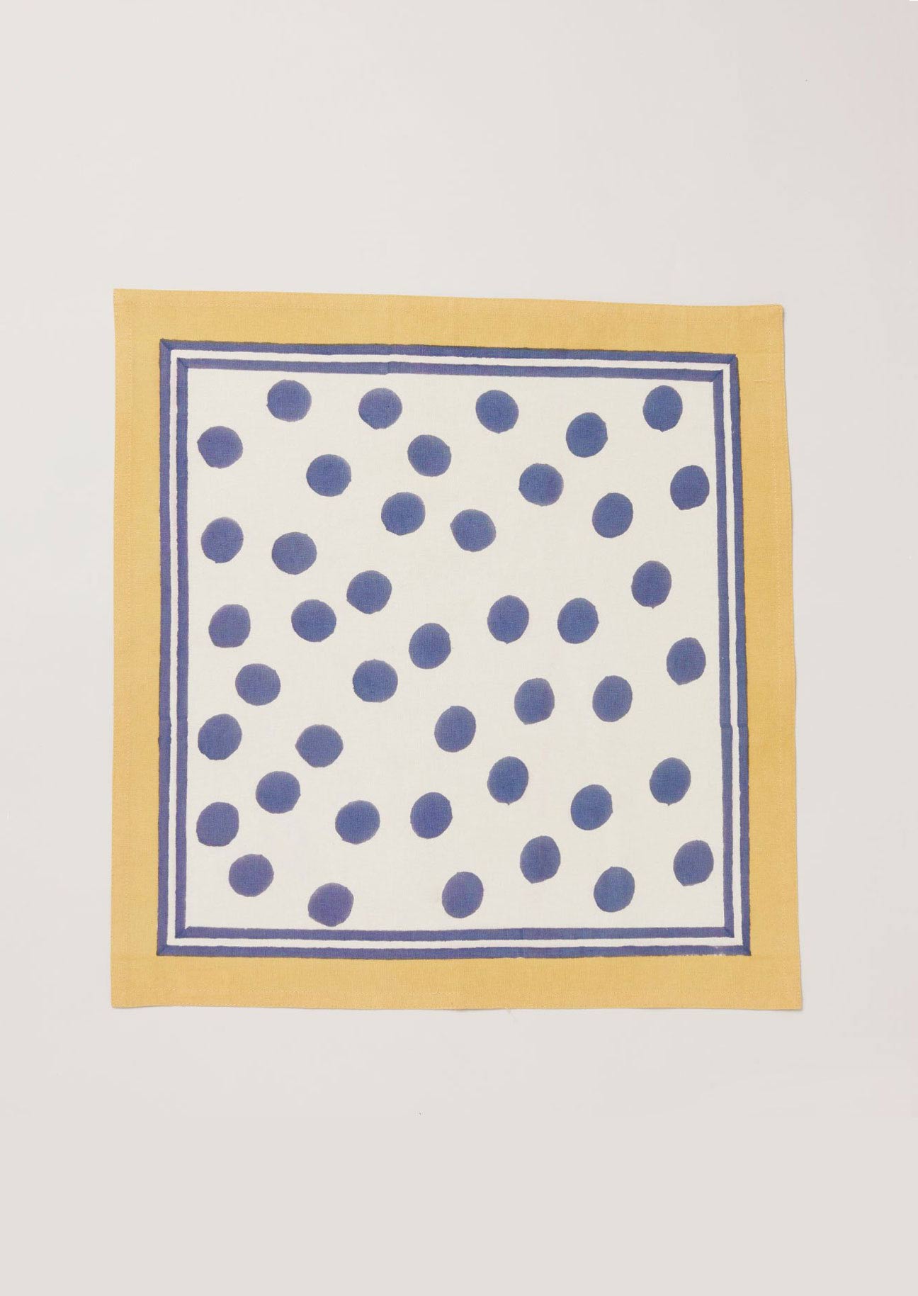 Single navy dot and yellow border napkin block printed onto white cotton.