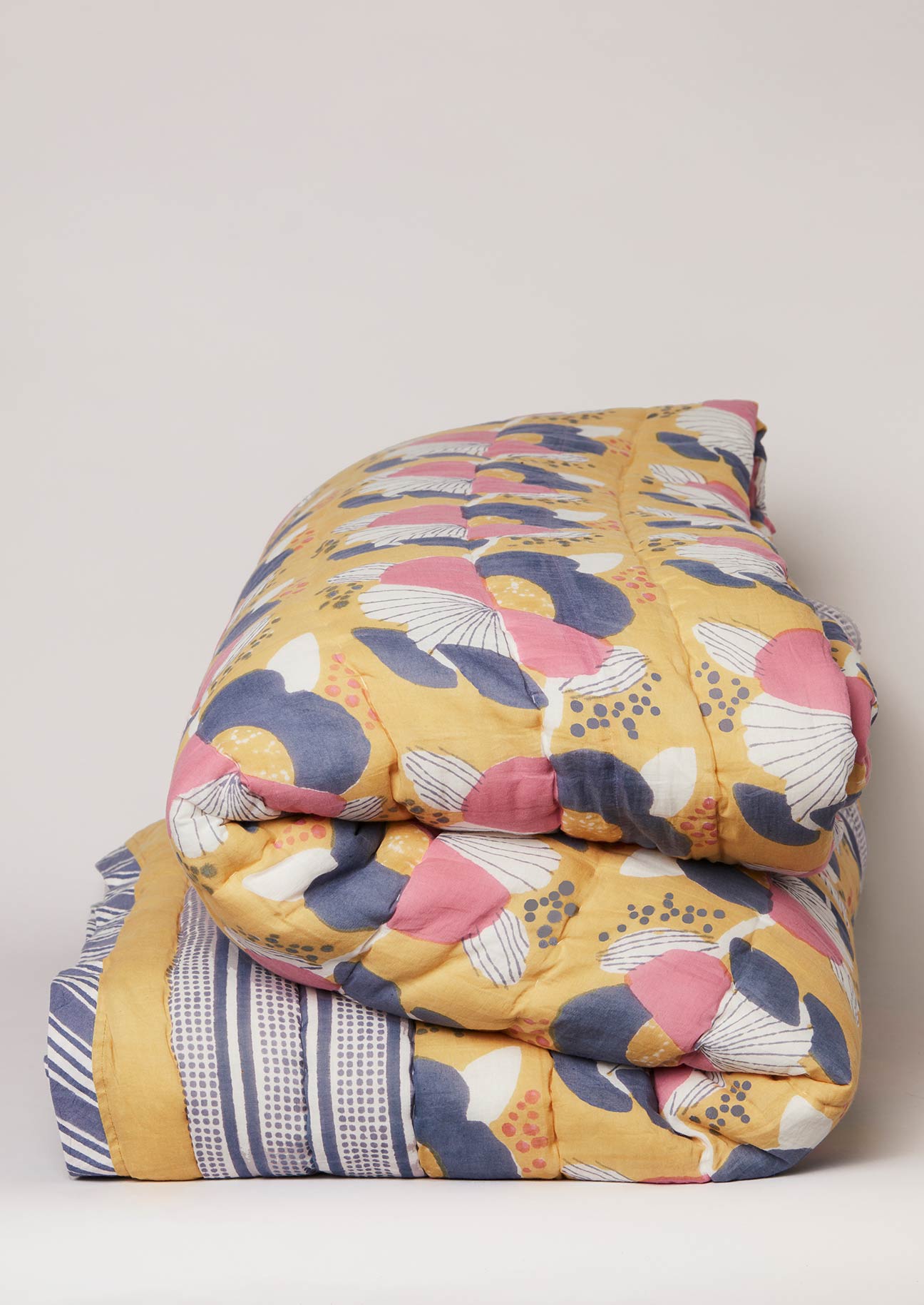Ochre, navy and pink floral block printed quilt with stripe border.