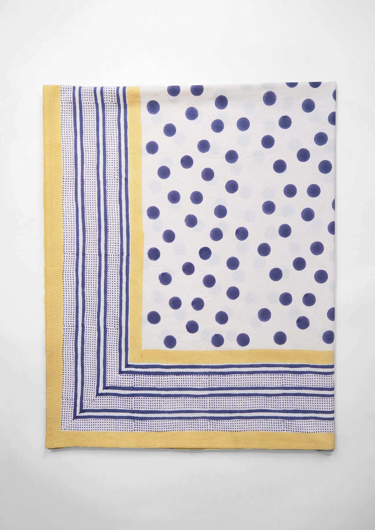 Hand block printed tablecloth in navy dot and yellow border on white ground.