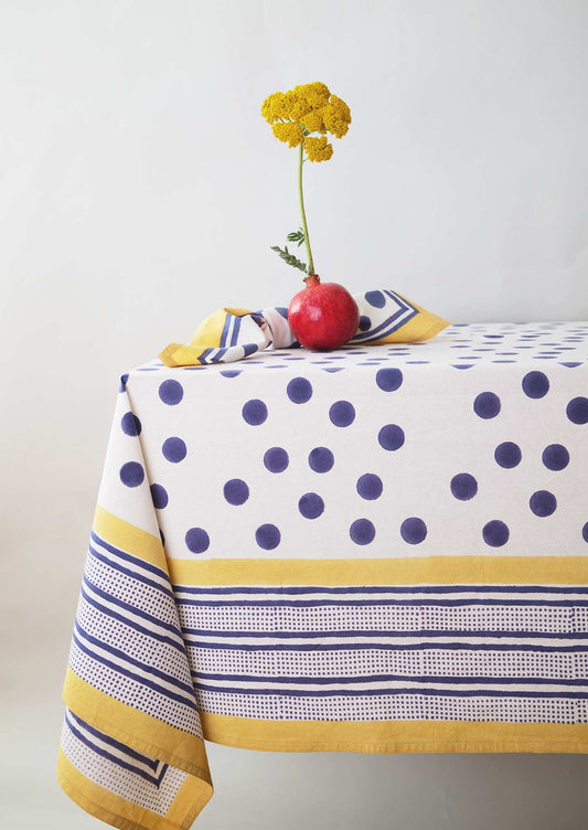 Table setting with co-ordinating tablecloth and napkin in a block printed navy spot on a white fabric base.