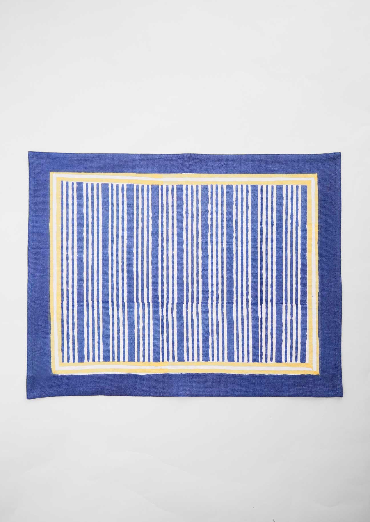 Single tablemat in block printed irregular stripe with solild navy edging and yellow stripe border detail.