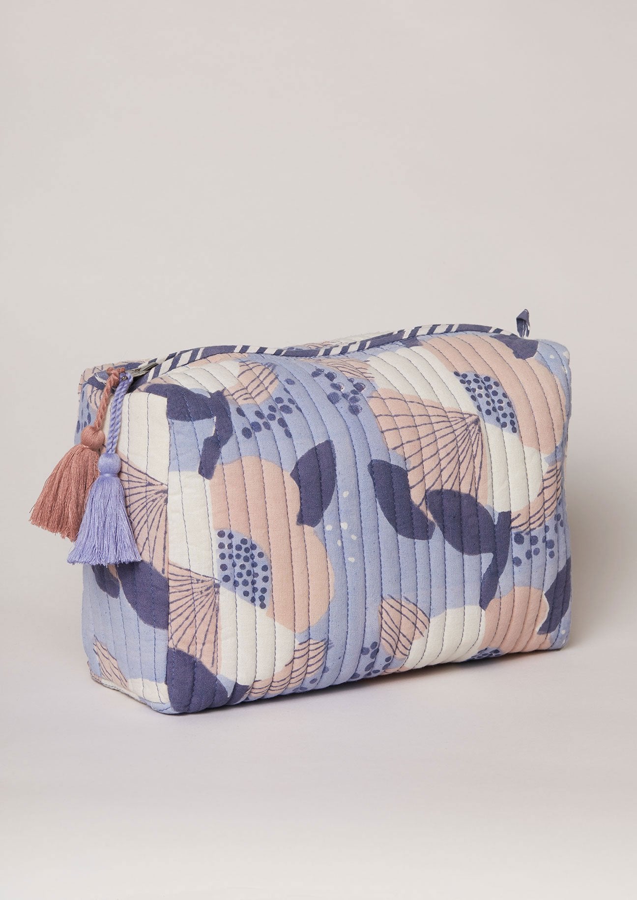 Side detail of blue block print toiletry bag with tassel decoration.